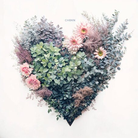 A composition of green leaves and pink flowers in the shape of a heart.